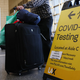 People wait in line to check in near a sign pointing to a COVID-19 testing area in the Tom Bradley International Terminal at Los Angeles International Airport (LAX) amid a COVID-19 surge in Southern California on December 22, 2020 in Los Angeles, California.